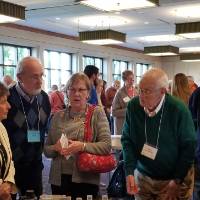 An older woman asks a younger woman a question while other older people listen
